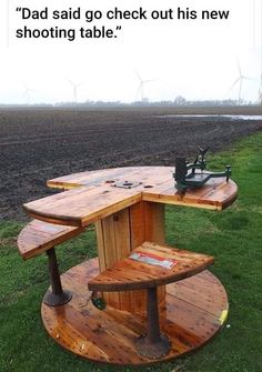 a wooden table sitting on top of a lush green field