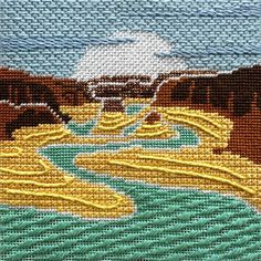 a cross stitch picture of cattle crossing a river in the mountains with yellow stream running through it