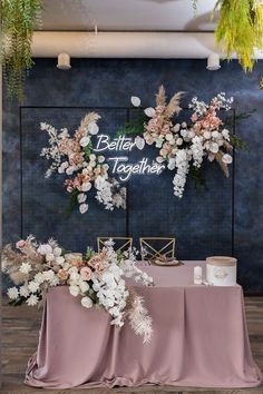 the table is set up with pink linens and white flowers on it, along with greenery