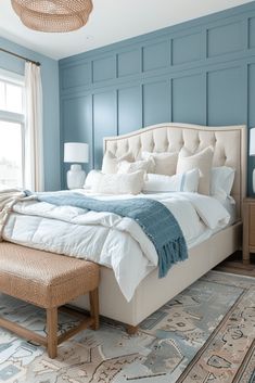 a bedroom with blue walls and white linens on the bed, along with an ottoman