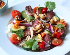 a white plate topped with meat and veggies next to a bowl of rice