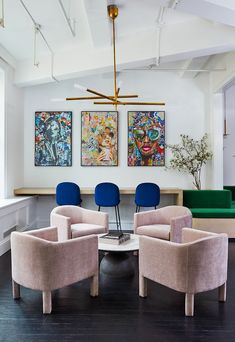 a living room filled with furniture and paintings on the wall