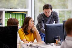 two people in an office setting looking at computers