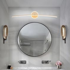 a bathroom with a round mirror above the sink and marble counter top, along with two gold faucets