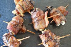 several skewered meats are sitting on a black plate with toothpicks