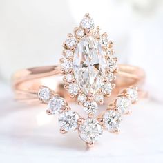 a close up view of a ring with an oval shaped diamond surrounded by smaller round diamonds