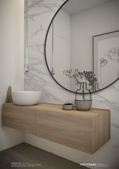 a white bowl sitting on top of a wooden counter next to a mirror and vase