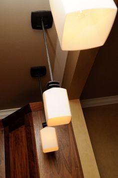 two square lights are hanging from the ceiling in a room with wood floors and walls