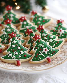 decorated christmas cookies on a plate next to a christmas tree