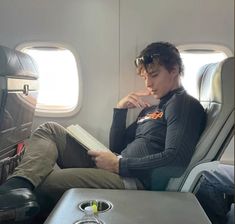 a man sitting on an airplane reading a book