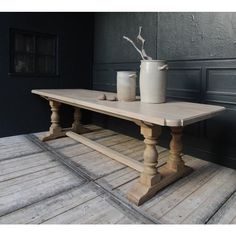 a wooden table with two white vases on it and a black wall in the background