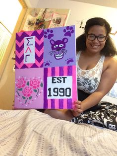 a woman sitting on her bed holding up a sign that says est190 and has an image of a cat