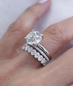 a woman's hand with a diamond ring and wedding band on top of her finger