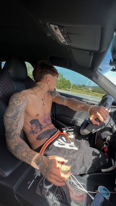 a tattooed man sitting in the driver's seat of a car