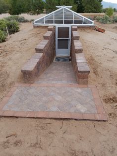 an outdoor kitchen is built in the middle of a dirt area with steps leading up to it