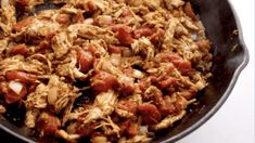 a skillet filled with meat and vegetables on top of a table