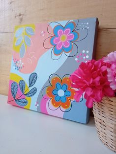 a basket with pink flowers sitting next to a painting