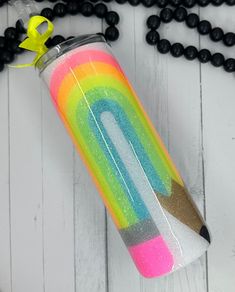 a colorful water bottle with a pencil sticking out of it on a white wooden surface