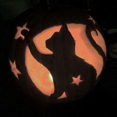 a carved pumpkin with a silhouette of a cat in the center and stars around it