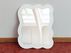 a white mirror sitting on top of a red carpeted floor next to a window