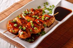 chicken skewers with sauce and green onions on a plate