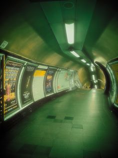 an empty subway station with posters on the walls