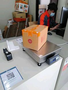 a man wearing a face mask sitting at a desk with boxes on top of it