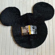 the mickey mouse rug is black and has a yellow tag on it's ear