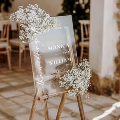 a sign with baby's breath flowers on it sitting in front of a table