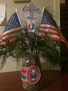 an american flag in a mason jar filled with sand and silver flakes, sitting on top of a wooden table