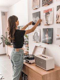 a woman standing in front of a wall with pictures on it and an old record player