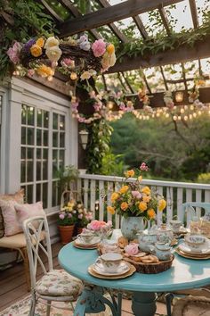 a blue table topped with plates and cups filled with flowers on top of a wooden deck