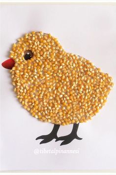 a bird made out of corn sitting on top of a white table next to a piece of paper