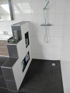 a bathroom with tiled floors and walls, including a stand up shower stall in the corner