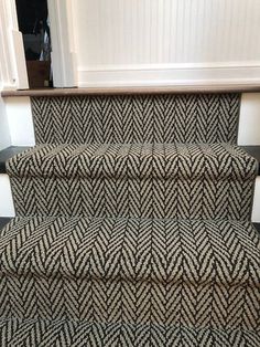 a carpeted stair case with black and white herringbones on the riser