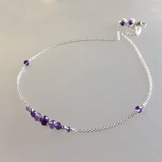 Genuine, premium-quality purple amethyst gemstone choker in sterling silver. This very dainty choker/necklace features genuine, premium-quality, faceted amethyst gemstones of varying size and shade, arranged in a bar that is wire-wrapped onto a dainty but strong sterling silver chain and finished with a sterling silver lobster claw clasp.  Two small beads are placed about 1.5 inches from the bar. Please note the photos of this necklace have been enlarged to show material and craftmanship. An elegant and minimalist choker that's perfect by itself or layered with other necklaces. Details: length: please choose at check out genuine faceted purple amethyst beads: 4.5 mm, 3.5 mm, 3 mm, 2mm sterling silver bead: 2.5mm sterling silver chain, clasp & other metal components Thanks for visiting ! Ba Affordable Dainty Purple Jewelry, Minimalist Amethyst Purple Necklace, Purple Round Beads Choker As A Gift, Purple Amethyst Crystal Necklace With Adjustable Chain, Purple Amethyst Choker Jewelry, Purple Amethyst Choker, Adjustable Purple Birthstone Necklace, Purple Choker, Dainty Choker Necklace