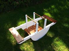 a wooden toy boat sitting on top of green grass