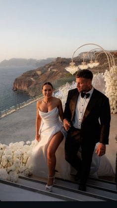 a man and woman sitting on steps next to each other in formal wear, posing for the camera