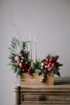 a wooden box filled with christmas decorations on top of a table next to a candle