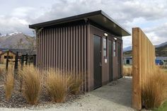 there is a small building that has grass in front of it and mountains in the background