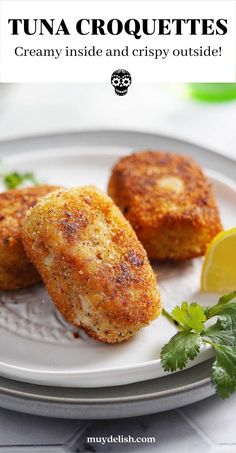 two crab cakes sitting on top of a white plate next to a lemon wedge and parsley