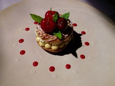 a small dessert with cherries and nuts on a white plate covered in water droplets