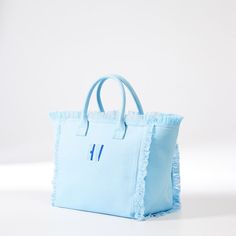 Bold, bright and generously sized, this beach-ready canvas bag has smart details like zipper closure, fringed edging, soft lining, two interior pockets and colors that spark joy. Made by Monogram Mary, from durable canvas, the two-toned embroidered monogram adds a personal touch.  17" w x 10.5" d x 8.5" h  Handle drop: 5"  Three interior pockets. Double open: 9" w x 5" h; Zipper: 7" w x 5.5" h  Canvas.  Spot clean.  Imported.  Monogramming is embroidered   Ships directly from the designer. Ships Blue Canvas Bag For The Beach, Blue Fringe Bags For Daily Use, Summer Blue Fringe Bag, Blue Fringed Bags For Vacation, Blue Cotton Canvas Bag For Weekend, Blue Fringe Tote Shoulder Bag, Blue Canvas Tote Beach Bag, Blue Canvas Beach Tote Bag, Blue Canvas Bags For Weekend