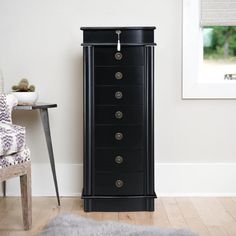 a tall black cabinet sitting next to a chair