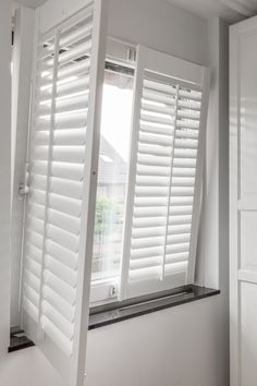 an open window with white shutters in a room