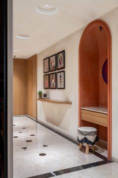 an entry way with pictures on the wall and a bench in the hallway between two rooms