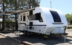 an rv is parked in the gravel near some trees