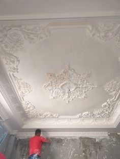 a man in red shirt painting a ceiling with white paint on the walls and ceilings