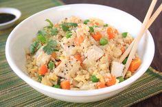 a white bowl filled with rice and veggies next to two chopsticks