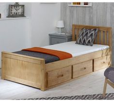 a bed with two drawers underneath it and a clock on the wall behind it in a bedroom